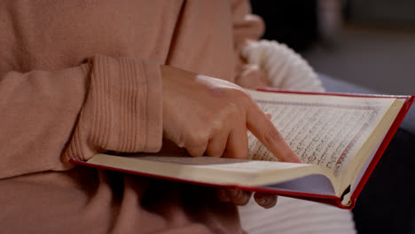 Close-Up-Of-Muslim-Woman-Sitting-On-Sofa-At-Home-Reading-Or-Studying-The-Quran-6